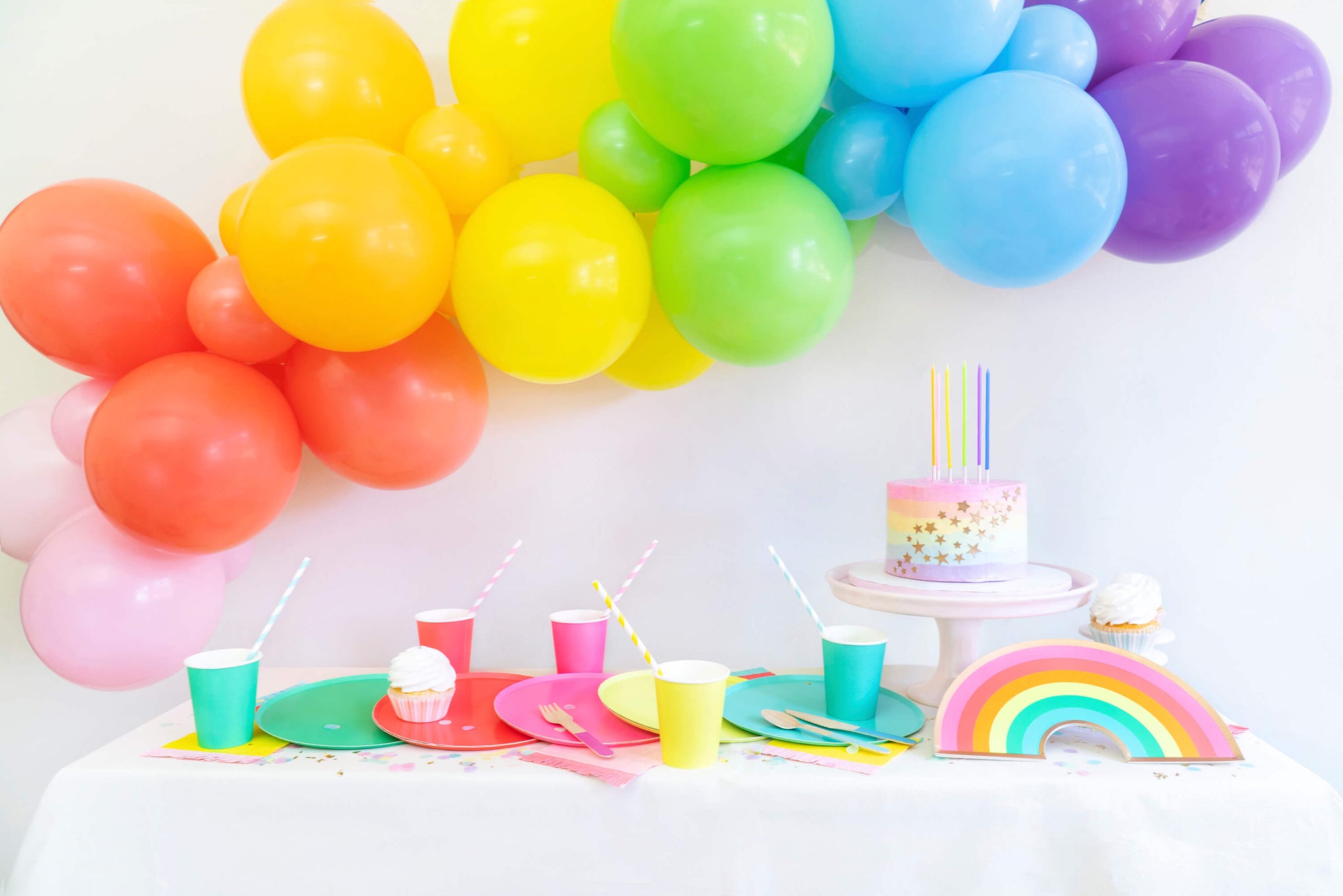 A bright birthday party table with cake and balloons